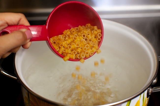 pasta being poured into a boiling pot of water