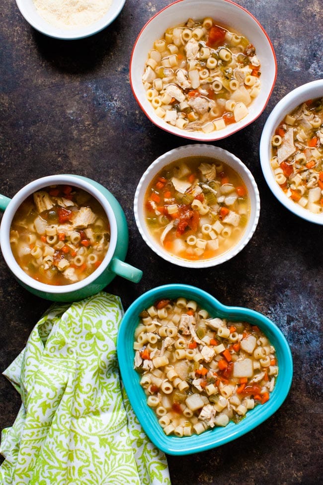 Chicken noodle soup in various shaped bowls with a green towel