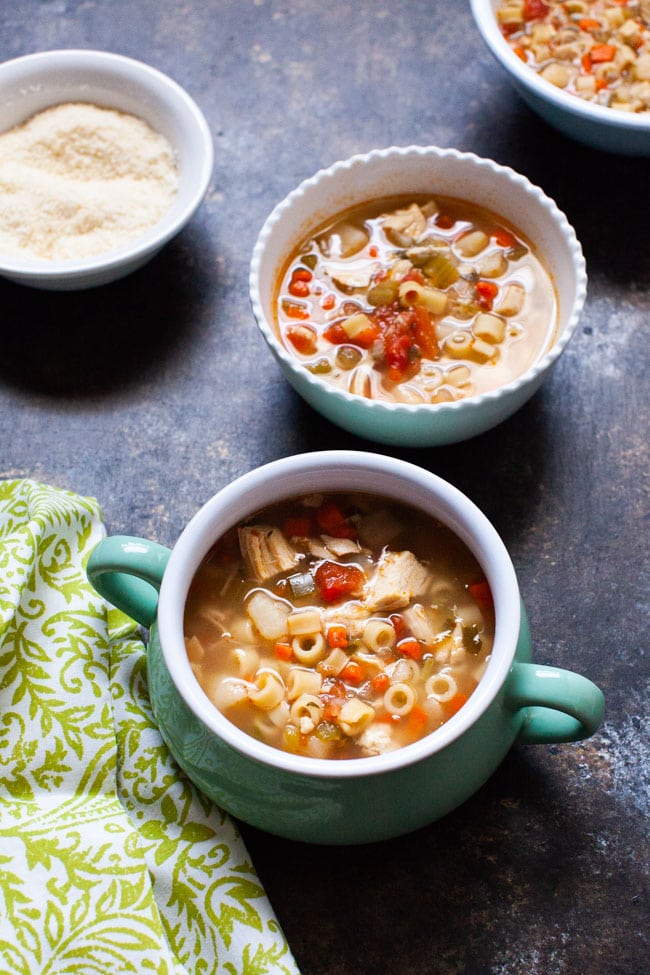 Spicy Chicken Soup in three different sized bowls and a bowl of parmesan cheese