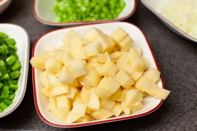 chopped russet potatoes and other vegetables in the background