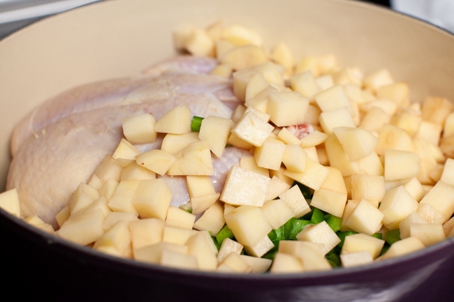 chopped russet potatoes in a pot with a whole chicken