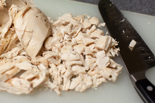 cooked chopped chicken on a cutting board with a knife