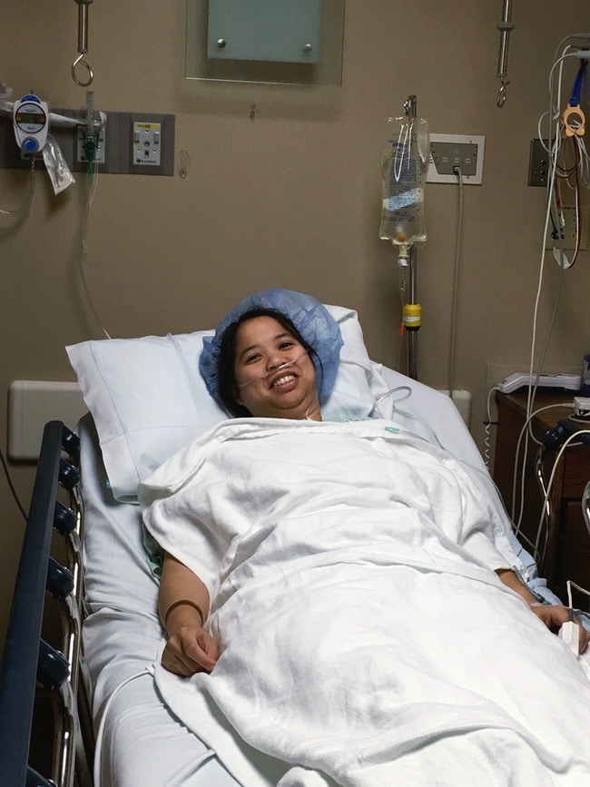 a woman laying in a hospital bed with a hair net on with white blankets