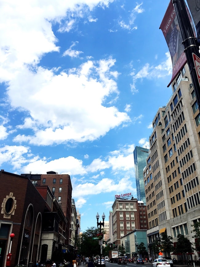 photo of a Boston street with towering buildings and a blue sky