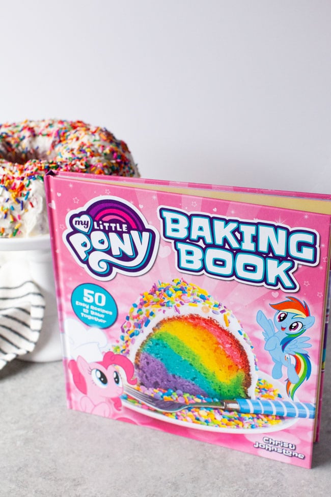 My Little Pony Baking Book standing in front of tray of rainbow bundt cake