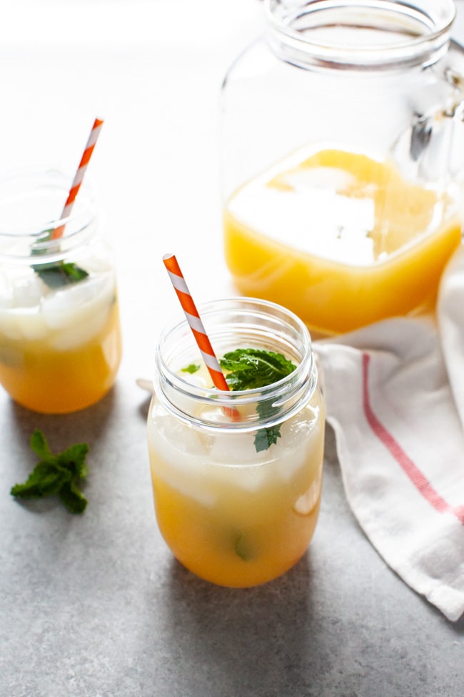 orange mint tea in a mason jar with a jug in the background