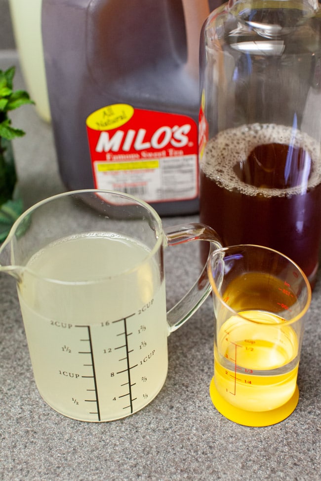 lemonade in a measuring cup with vodka, sweet tea in a carrafe on a counter