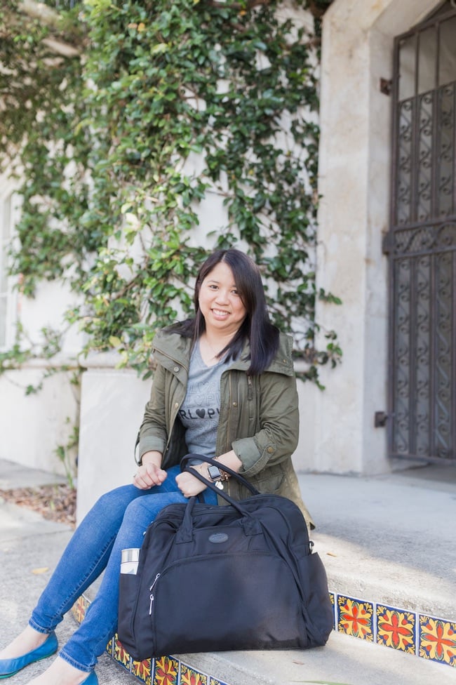 a woman sitting on the sidewalk with a travel carry on bag