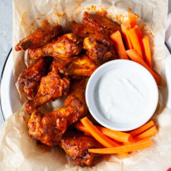 buffalo chicken wings from the air fryer in a pan with carrots and blue cheese dipping sauce