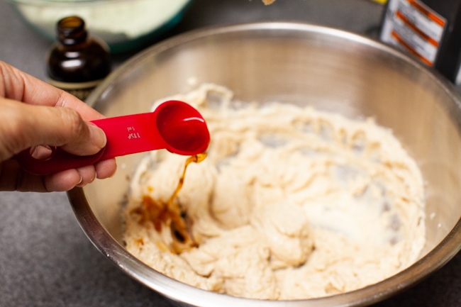 Pouring teaspoon of vanilla extract into Matcha Cookie batter from thelittlekitchen.net