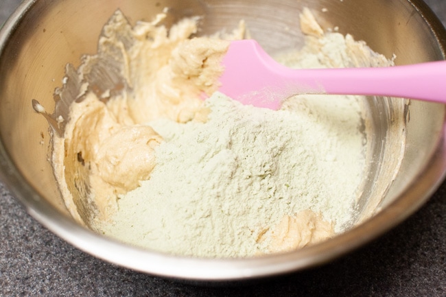 Adding dry mixture to wet mixture in metal mixing bowl for Matcha Cookies from thelittlekitchen.net