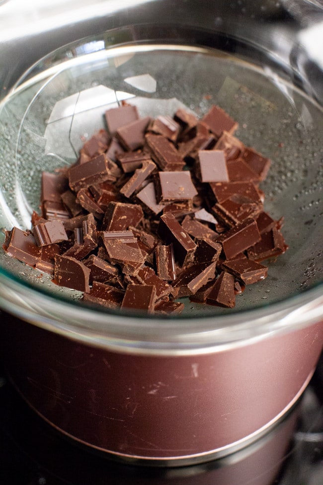 Chocolate pieces melting in a glass bowl set over a pot of bowling water from thelittlekitchen.net