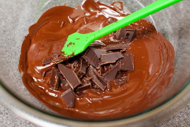 Stirring melted chocolate in a glass bowl with a green spatula from thelittlekitchen.net
