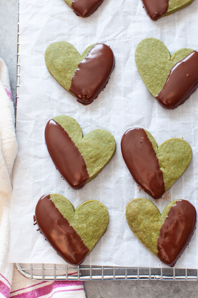 Heart Shaped Matcha Cookies Dipped in Chocolate on White Parchment Paper from thelittlekitchen.net