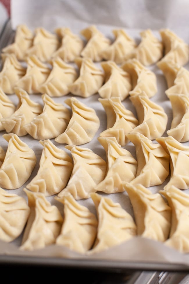 Parchment-lined baking sheet with uncooked Vegetarian Dumplings from thelittlekitchen.net