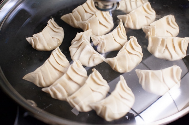 Vegetarian Dumplings cooking in a covered skillet from thelittlekitchen.net