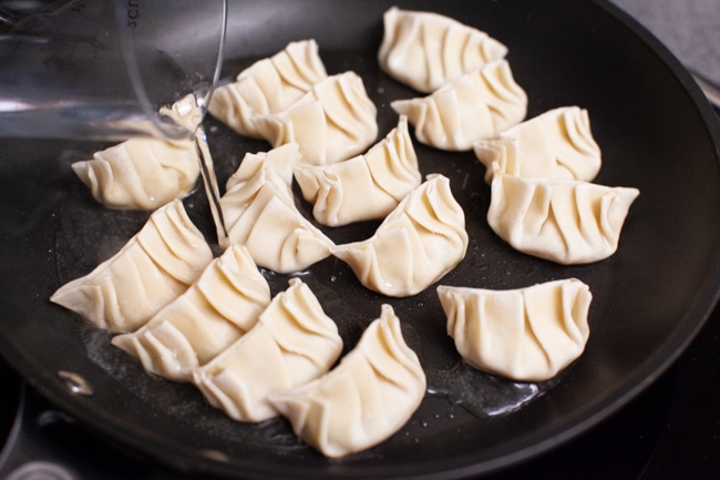 Water being poured into skillet of Vegetarian Dumplings from thelittlekitchen.net