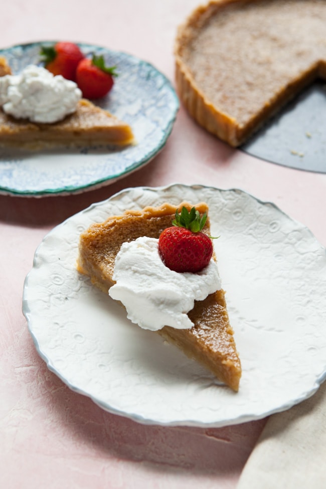 Two slices of Sugar Pie topped with whipped cream and strawberries