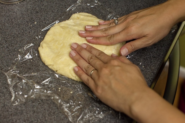 Hands pressing pie dough into circle