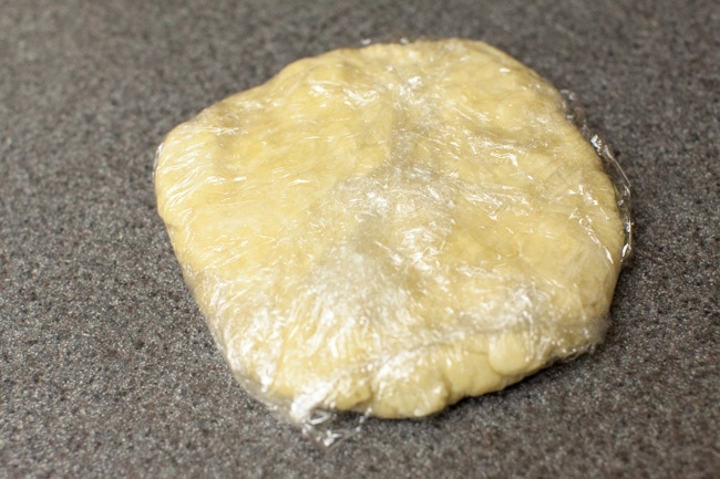 Circle of pie crust dough in plastic wrap