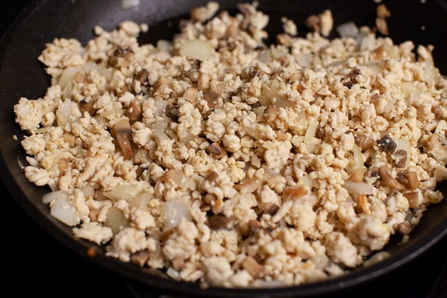 Skillet with cheeseburger egg roll filling cooking