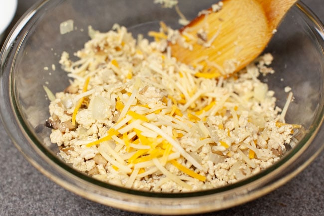 Glass bowl with cheeseburger egg roll filling and a wooden spoon