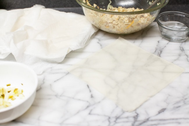 egg roll wrapper on marble slab with egg roll filling in the background