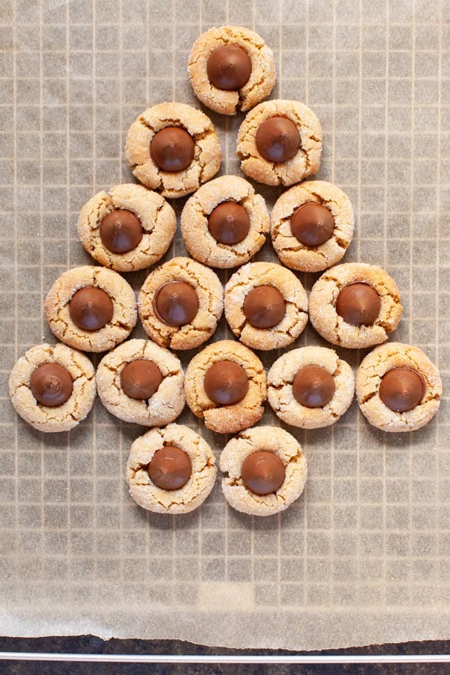 Peanut Butter Blossom Cookies on a baking sheet with a cooling rack and parchment paper underneath. 