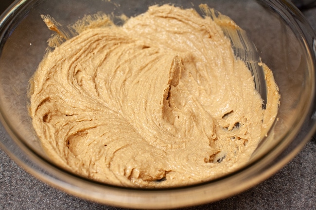 A mixture of peanut butter, shortening, sugar, and brown sugar in a glass bowl. 