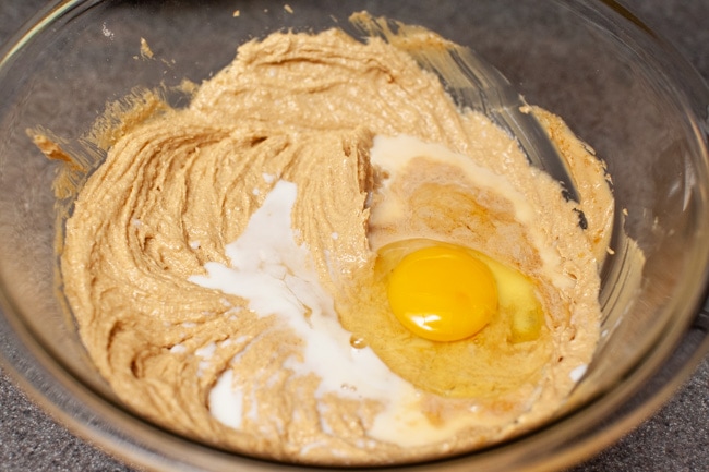 Milk and egg in a glass bowl with a peanut butter cookie dough. 