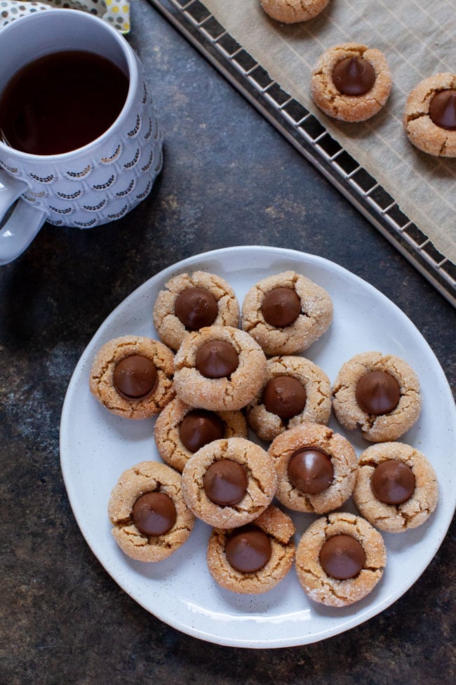 Peanut Butter Blossoms on a white plate next to a cup of coffee. 