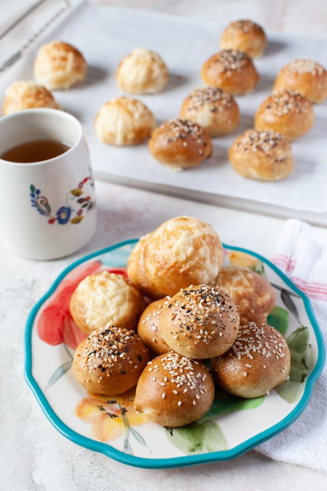 stuffed bagel bites on a floral plate with a cup of tea in the background along with more stuffed bagel bites