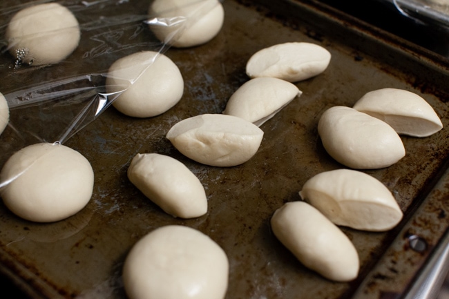 Rhodes dinner rolls cut in half on a baking sheet