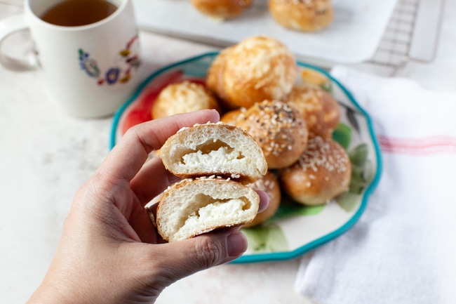 a stuffed bagel bite cut in the middle showing the cream cheese inside, a cup of tea in the background along with more stuffed bagel bites