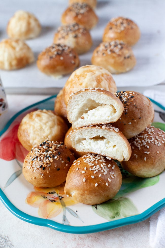 a stuffed bagel bite cut in the middle showing the cream cheese inside and in the background along with more stuffed bagel bites