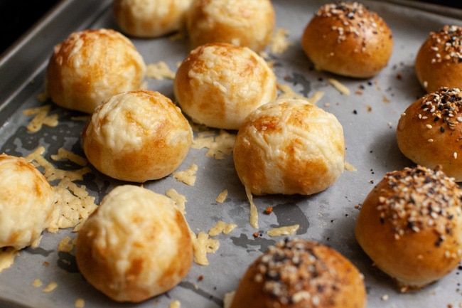 stuffed bagel bites with toppings on a parchment paper lined baking sheet right out of the oven