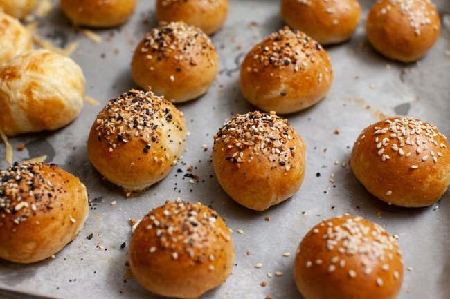 stuffed bagel bites with toppings on a parchment paper lined baking sheet right out of the oven