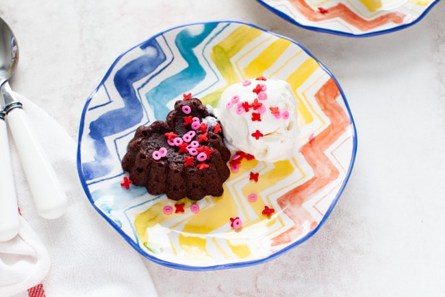 heart shaped chocolate cake with vanilla ice cream on a plate with spoons