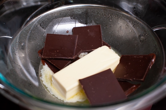 chocolate bars and butter in a bowl on top of a pot