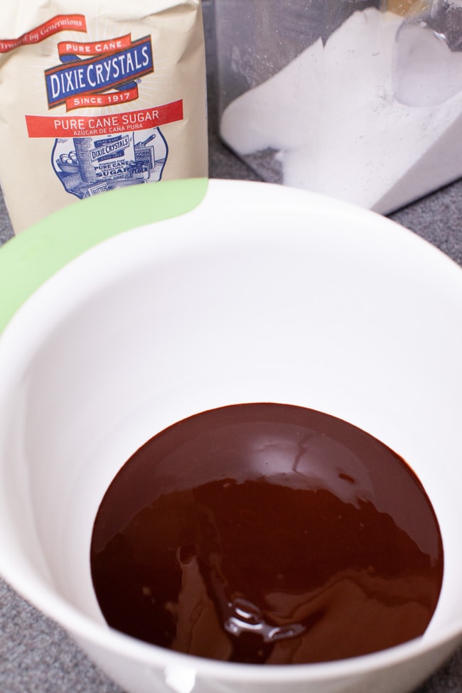 melted chocolate in a mixing bowl with sugar in the background