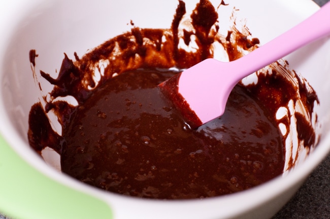 chocolate cake batter in a mixing bowl with a pink rubber spatula