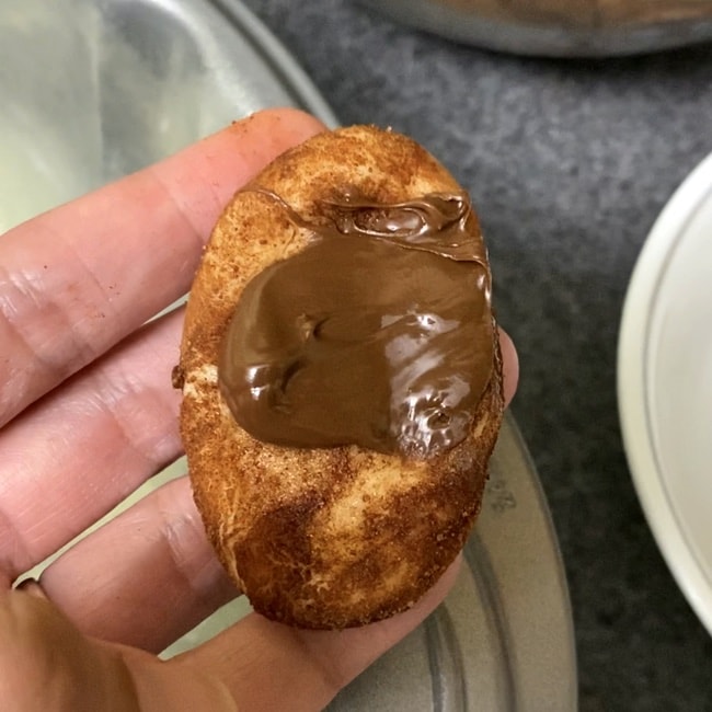 a hand holding Monkey Bread dough with nutella spread