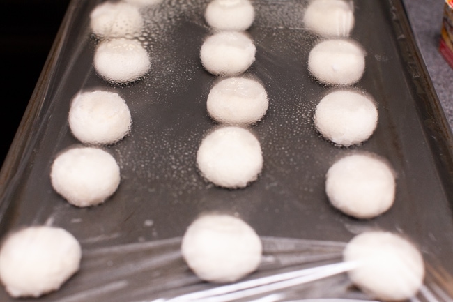 Yeast Rolls on a baking sheet covered with plastic wrap.