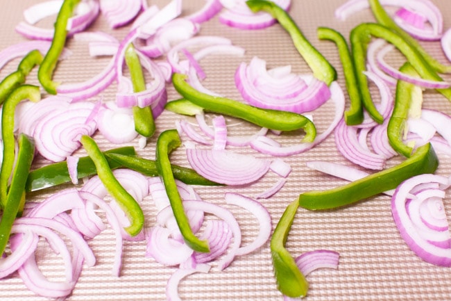 red onions and bell peppers on a baking sheet