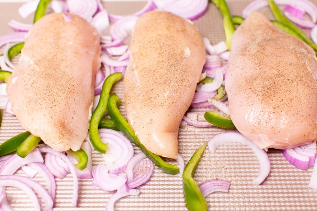 chicken, red onions and bell peppers on a baking sheet