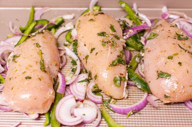 chicken, red onions and bell peppers on a baking sheet
