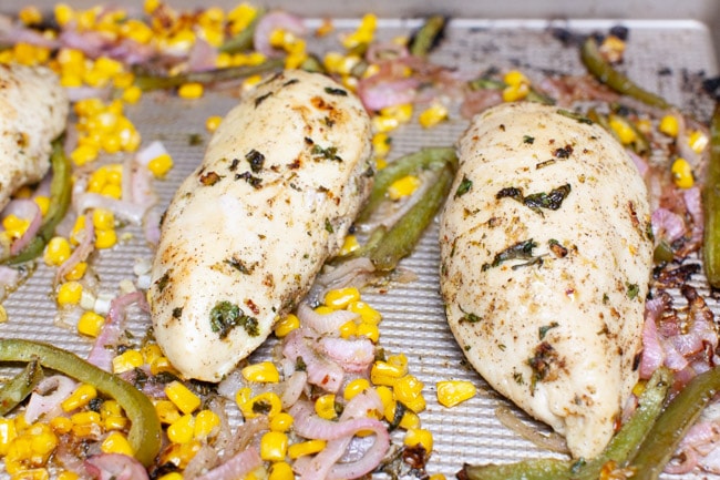 chicken, red onions and bell peppers on a baking sheet