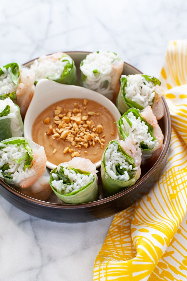 Vietnamese Spring Rolls cut up in a bowl with peanut dipping sauce on a plate with a napkin in the background