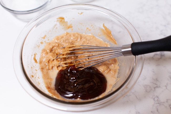 making peanut sauce in a glass bowl with a whisk