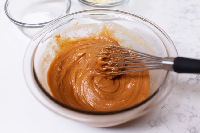 almost done making peanut sauce in a glass bowl with a whisk